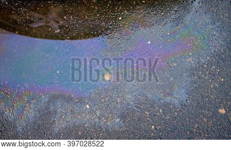 Colorful Gas Stain On Wet Asphalt. Oil Stain Caused By A Leak Under A Car