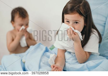 The Little Girl Caught A Cold. Children Sneeze Into A Handkerchief. The Child Is Ill And Is Being Tr