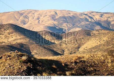Sun Setting On Arid Rolling Hills With Grasslands Creating Natural Shadows During Sunset Taken In Th