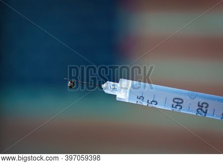 Close-up Of A Syringe With The United States Flag Waving On The Background