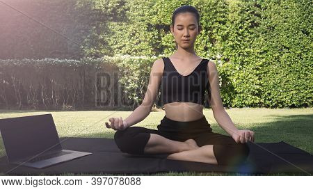 A Sporty Woman Or Online Instructor In Sportswear Is Sitting And Practicing Yoga