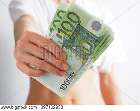 In The Outstretched Female Hand, 100 Euro Bills. The Woman Holds Out The Money. The Concept Of Wealt