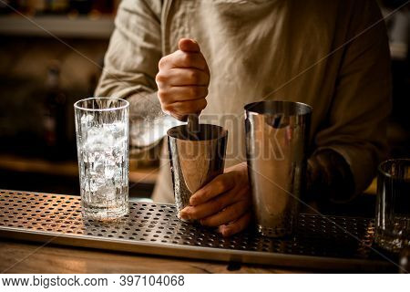 Bartender Prepares Cocktail In Shaker Cup Using The Muddler