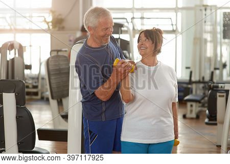 Happy Couple Of Seniors Training At Gym Together. Smiling Elderly Couple Looking At Each Other Durin