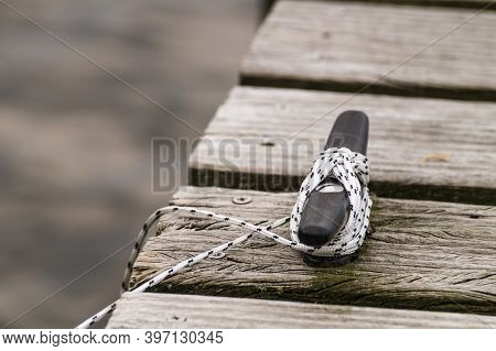 Boat Rope Secured To Cleat On Wooden Boating Dock Or Pier.