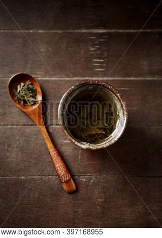 Green Tea (sencha) In A Traditional, Japanese Tea Cup And Sencha Leaves On A Wooden Tea Spoon. Dark 