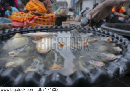 Blurred Image Of Alive Fishes For Sale. Aged Woman Selling Them In A Fish Market In Territy Bazar, K