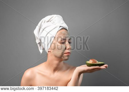 Beautiful Young Woman With Facial Mask And Fresh Avocado. Nature Mask On Face, Skincare Cleansing Ec