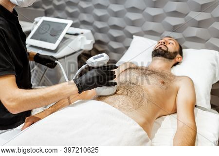 Man During An Ultrasound Liposuction Procedure At Luxury Spa Salon. Doctor Working On Abdomen Area