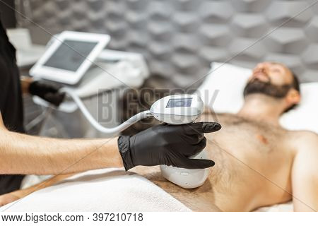 Man During An Ultrasound Liposuction Procedure At Luxury Spa Salon. Doctor Working On Abdomen Area