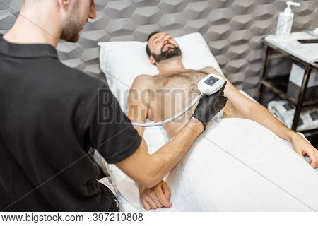 Man During An Ultrasound Liposuction Procedure At Luxury Spa Salon. Doctor Working On Abdomen Area