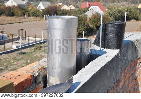 The Construction Of A Brick Chimney With Two Flues, Steel Pipes Installed At Different Hight. Buildi