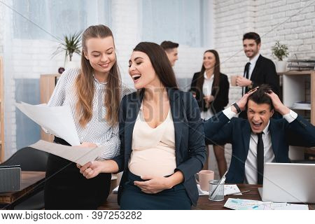 Two Young Girls Are Laughing At Work Annoying Boss. Two Women Are Standing In The Office With Papers