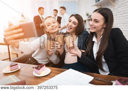 Two Young Girls Are Laughing At Work Annoying Boss. Two Women Are Standing In The Office With Papers