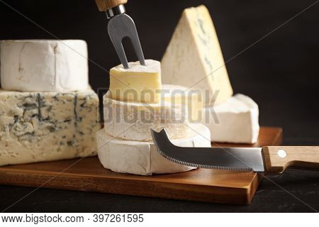 Different Types Of Cheese, Knife And Fork On Black Table, Closeup