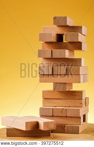 The Concept Of Entrepreneurial Risk With The Jenga Model. Wooden Blocks On A Yellow Background