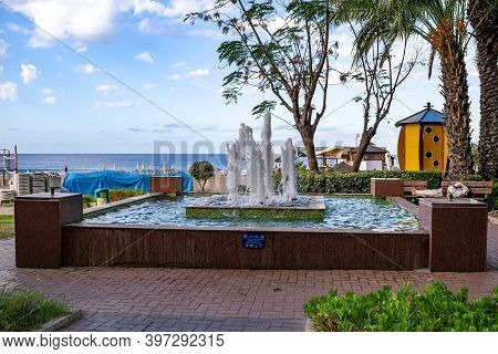 Turkey, Alanya - October 22,2020: Homeless Man Sleeps On A Bench Near A Fountain In Alanya Park. Hou
