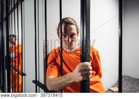 Psychological Portrait Of An Evil And Wild Prisoner Through The Bars Of A Prison Cell. A Strong Look