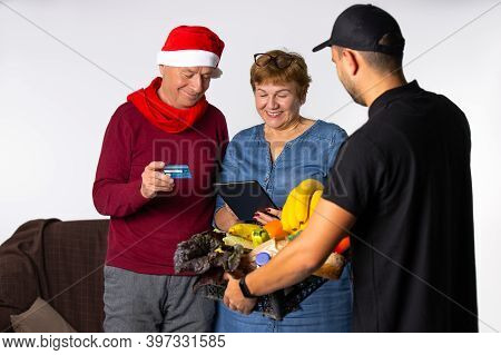 The Older Family Pays For The Christmas Groceries Ordered By The Courier Service With A Credit Card.