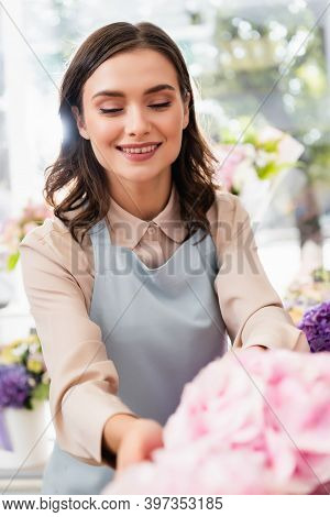 Female Florist Looking At Blurred Hydrangeas On Foreground