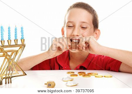เด็กชาย dreidel เล่นและกินช็อกโกแลต Hanukkah gelt  พื้นหลังสีขาว