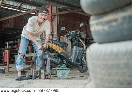 The Tire Patcher Smiles Looking At The Camera While Preparing A Traditional Press Before Patching Th