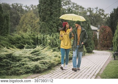 Young Couple Under Yellow Umbrela Looking Happy