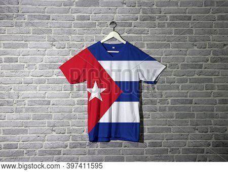 Cuba Flag On Shirt And Hanging On The Wall With Brick Pattern Wallpaper, Blue And White With The Red