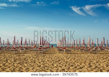 Sunlongers sulla spiaggia di sabbia e ombrelloni ritirati