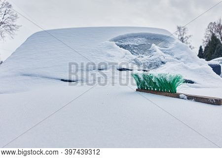 Green Snow Brush Lies On The Hood Of A Snow-covered Car
