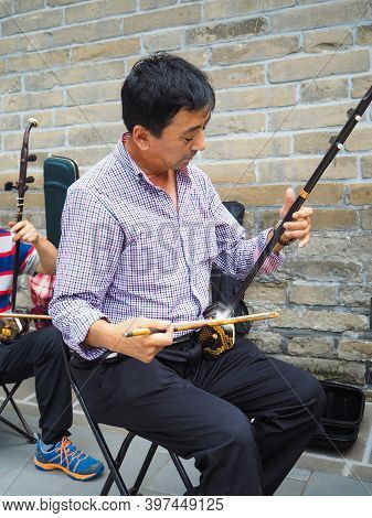 Beijing, China - September 2017: Chinese Man Playing The Chinese Violin Called Erhu In A Small Ensem