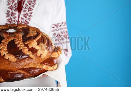 Woman Holding Korovai On Light Blue Background, Closeup With Space For Text. Ukrainian Bread And Sal