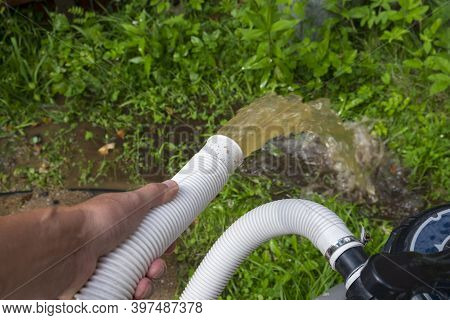 Backwash Of A Water Filter, A Hand Holding A Hose In The Foreground