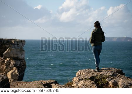 Woman In Sea Cliffs Landscape In Cabo Carvoeiro Cape Looking At Berlengas Island, In Peniche, Portug