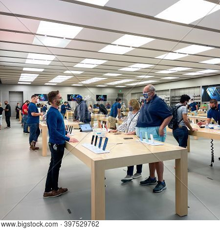 Salespeople And Customers At An Apple Store Looking At The Latest Apple Products For Sale.