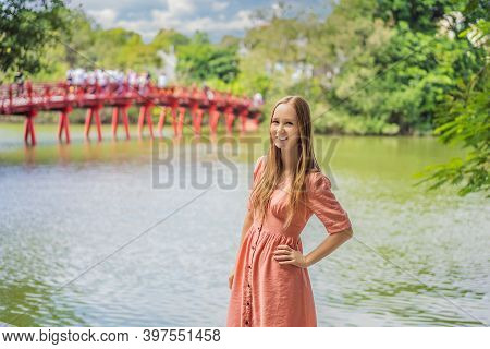 Caucasian Woman Traveler On Background Of Red Bridge In Public Park Garden With Trees And Reflection