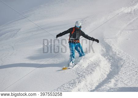 VALMOREL, FRANCE -CIRCA 2019: Anowboarder coming down fast in fresh powder snow off-piste free ride. Plowing snow