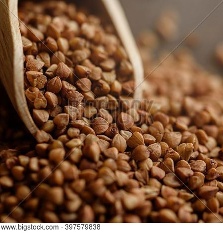 Scoop And Buckwheat Macro View On Rustic Background. Close Up Raw Buckwheat Background. Gluten Free 