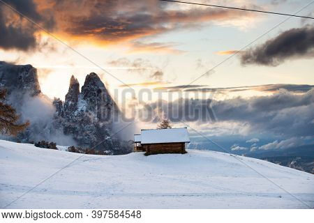 Small cottage in magic sunset in Dolomite mountains, Alpe di Siusi, Italy in winter