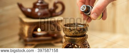 Hand Of Therapist Pours Drops Of Essential Oil To A Ceramic Diffuser In Spa Salon