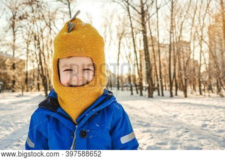 Boy Amile And Squinted At Sun. Winter, Park, Copy Space. Close-up Portrait.