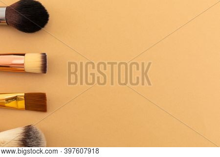 High angle view of selection of makeup brushes on yellow background. beauty grooming copy space concept.