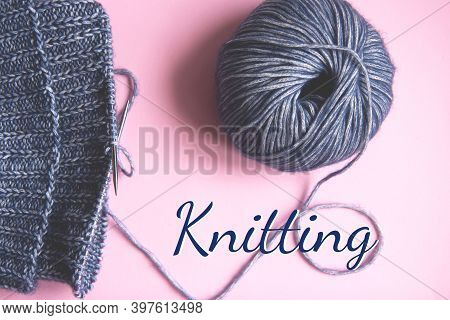 Knitting Project Underway. Knitting With A Ball Of Blue Yarn And Knitting Needles On Pink Background