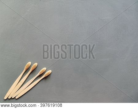 A Family Set Of Four Wooden Toothbrushes On Grey Background With Copy Space
