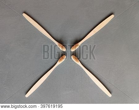 A Family Set Of Four Wooden Toothbrushes On Grey Background With Copy Space
