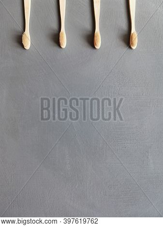 A Family Set Of Four Wooden Toothbrushes On Grey Background With Copy Space
