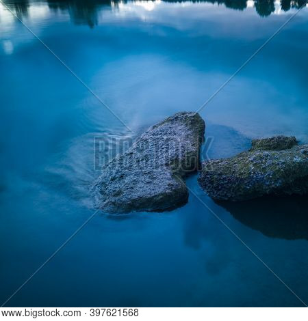 Intimate Landscape With Rocks And Streaming Rippling Water During Blue Hour. Calm Riverine Detail.