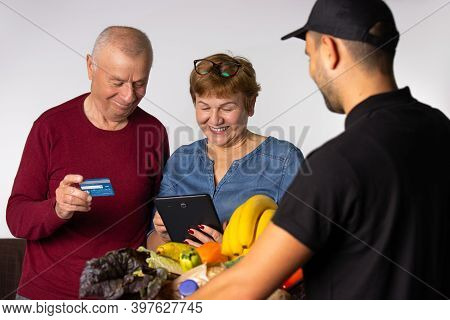 The Older Family Pays By Credit Card For Order Delivery By The Courier Service. White Background.