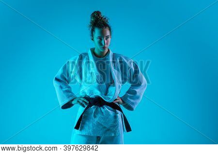 Posing. Professional Female Judoist In White Judo Kimono Practicing And Training Isolated On Blue Ne