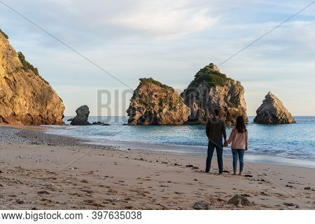 Couple Holding Hands On A Wild Empty Beach In Ribeiro Do Cavalo, Arrabida, Portugal